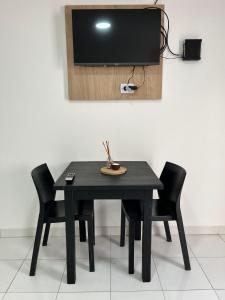 a black table with chairs and a tv on a wall at Del Estero in Santiago del Estero