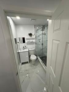 a white bathroom with a toilet and a shower at Adrien Guest Studio in Miami Gardens