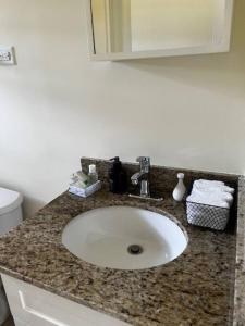 a bathroom counter with a sink and a mirror at BellaRose at Colbeck ,Gated with Pool, Stylishly modern in Old Harbour