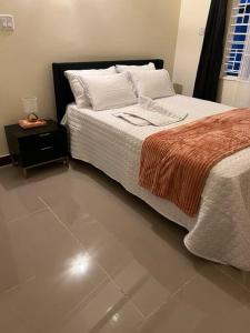 a bedroom with a bed and a night stand next to it at BellaRose at Colbeck Gated and Stylishly modern in Old Harbour