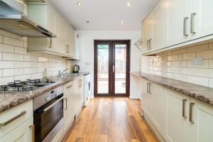 cocina grande con armarios blancos y suelo de madera en Modern House Just Refurbished, en Londres