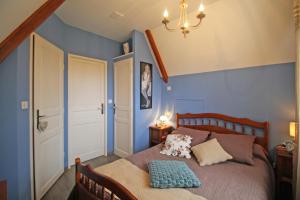 um quarto com uma cama com uma parede azul em Les deux chenes em Saint-Denis-des-Murs