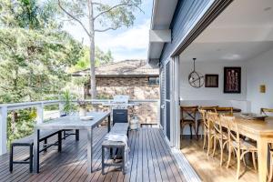 a deck with a table and chairs and a dining room at Bannister Head Beach House in Narrawallee