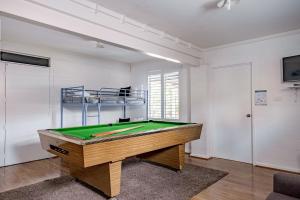 una mesa de ping pong en una habitación con piscina en Bannister Head Beach House, en Narrawallee
