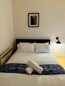 un letto con lenzuola e cuscini bianchi di Chic Urban Retreat a Londra