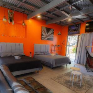 um quarto com 2 camas e uma parede laranja em Monkey garage en Orosi em Orosí