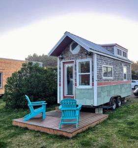 a tiny house with two blue chairs on a deck at Driftwood - Tiny Tranquility on the Oregon Coast in Waldport