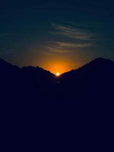 una puesta de sol sobre una montaña con el sol en el cielo en The Retro Glass House, en Mount Abu
