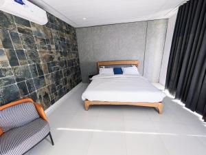 a small bedroom with a bed and a chair at The Retro Glass House in Mount Ābu