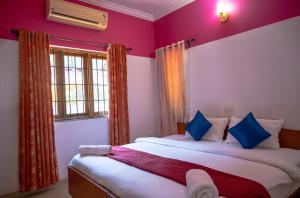 1 dormitorio con 2 camas, paredes de color púrpura y ventana en Franria Villa Guest House en Calangute