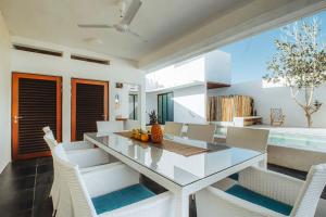 uma sala de jantar com uma mesa de vidro e cadeiras brancas em New La Manzanilla Paradise Vibrant Pool Home em La Manzanilla