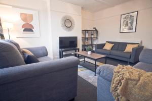 a living room with blue couches and a tv at May Disc - Long Stay - Contractors in Bristol