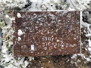 ein Schild im Schnee mit einem Haus darauf in der Unterkunft 제주 함덕해수욕장&룸4개&까페같은 감성숙소 in Hamdŏng-ni