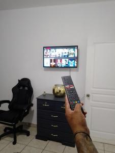 a person holding a remote control in front of a television at MI HOGAR in Tegucigalpa