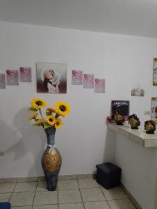 a vase with yellow flowers in a room with pictures at MI HOGAR in Tegucigalpa