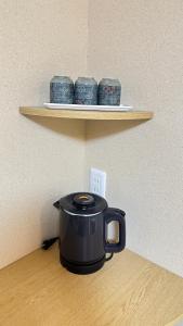 a black pot on a shelf with three blue dishes at Garden House Umenoya Otaru in Otaru