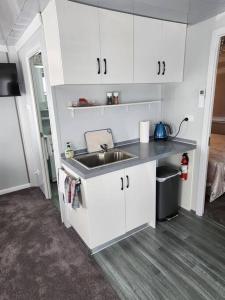 una cocina con armarios blancos y fregadero en Our Casetta, en Richmond
