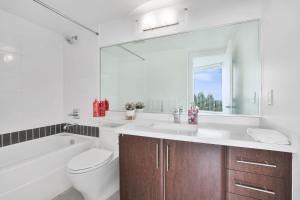 a bathroom with a sink and a toilet and a mirror at Sleek 2BR Getaway Urban Pulse Waterfront Tranquility in Vancouver