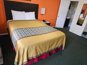 uma cama grande num quarto com uma parede laranja em Norvic Motel em Coniston