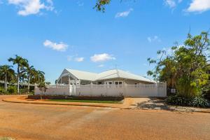 a house with a white fence in front of a road at Sandscapes Sanctuary in Broome