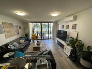 a living room with a couch and a tv at The Boathouse Luxury Apartments in Tea Gardens