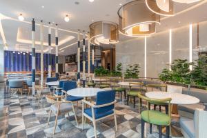 a restaurant with blue and green chairs and tables at Holiday Inn Express Changfeng Park in Shanghai