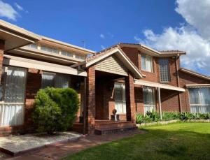 a brick house with a porch and a green lawn at The peaceful retreat in Mulgrave