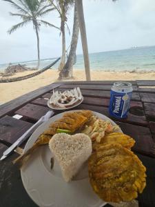 einen Teller Essen mit einem Sandwich auf einem Tisch neben dem Strand in der Unterkunft hospedaje en las islas de San blas habitacion privado con baño compartido in Achoertupo
