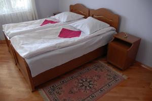 Una cama con sábanas blancas y almohadas rosas. en Hotel Elegant, en Kutaisi