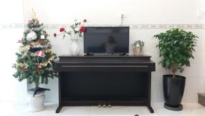 un piano negro con un árbol de Navidad y un televisor en Sunny Homestay Quy Nhơn en Quy Nhon