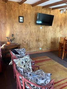 a living room with a chair and a television on a wall at Departamento en Pitrufquén in Pitrufquén