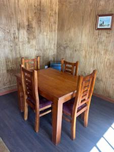 een houten eettafel met stoelen en een houten muur bij Departamento en Pitrufquén in Pitrufquén