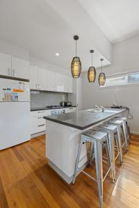 a kitchen with white cabinets and a large island with stools at Sail Away Inlet Side in Inverloch