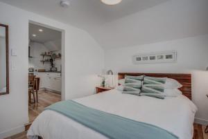 a bedroom with a white bed and a kitchen at Cozy 1BR Dine Play & Sip in Urban Mtn Paradise in Colorado Springs