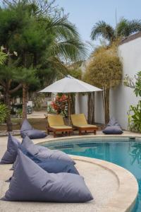 una piscina con 2 sillas y una sombrilla en Villa Rika, en Gili Trawangan