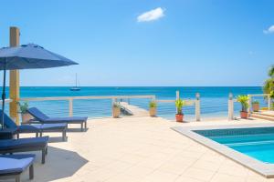 a swimming pool with chairs and an umbrella next to the ocean at Del Playa #1 Condo in West End