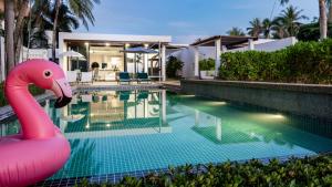 a pink inflatable flamingo in front of a swimming pool at AP Natai Luxury Beachfront Pool Villas in Phang-nga