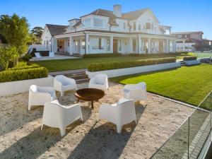 Casa blanca grande con sillas blancas y mesa en Hampton on View Luxury Clifftop in Campbells Bay, en Auckland