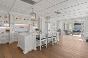 a large kitchen with white cabinets and a large island at Hampton on View Luxury Clifftop in Campbells Bay in Auckland