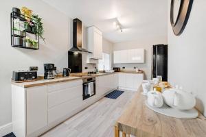 a kitchen with white cabinets and a wooden table at Pass the Keys Spacious Stylish House in Manchester