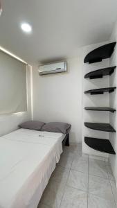 um quarto branco com uma cama e uma prateleira em apartamento Santa Marta-Rodadero Blanquita205 em Santa Marta