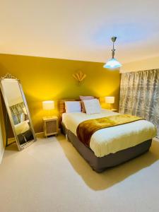 a bedroom with a bed and a yellow wall at Rosedale Retreat in Invercargill