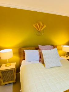 a bedroom with a bed with yellow walls and two lamps at Rosedale Retreat in Invercargill