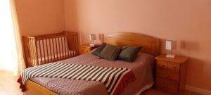 ラジェス・ド・ピコにあるCasa das Pedras Altasのベッドルーム1室(ベッド1台、ナイトスタンド2台、ベビーベッド1台付)