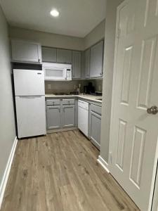 a kitchen with white appliances and a wooden floor at Cozy Aksarben Living-close to I-80 & WFH desk in Omaha