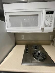 a microwave oven above a stove in a kitchen at Cozy Aksarben Living-close to I-80 & WFH desk in Omaha