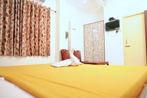 a bedroom with a bed with a yellow blanket on it at J S Residency in Nāgappattinam