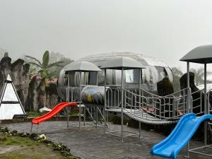 une aire de jeux avec des toboggans et des parasols en face d'un bus dans l'établissement Rayana Resort Mitra Reddoorz, à Songgoriti