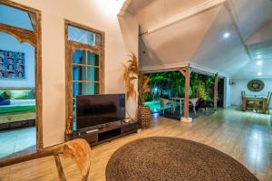 un salon décloisonné avec une grande télévision et une table dans l'établissement Legian Beach 3 Bedroom Villa, à Legian