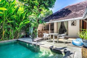 a house with a swimming pool and a table and chairs at Legian Beach 3 Bedroom Villa in Legian
